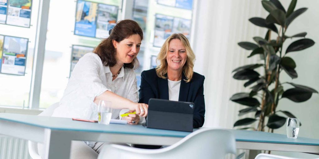 Sfeerbeeld van Sandra en Daniëlla bezig achter een computer voor Regron Makelaardij in Zoetermeer.